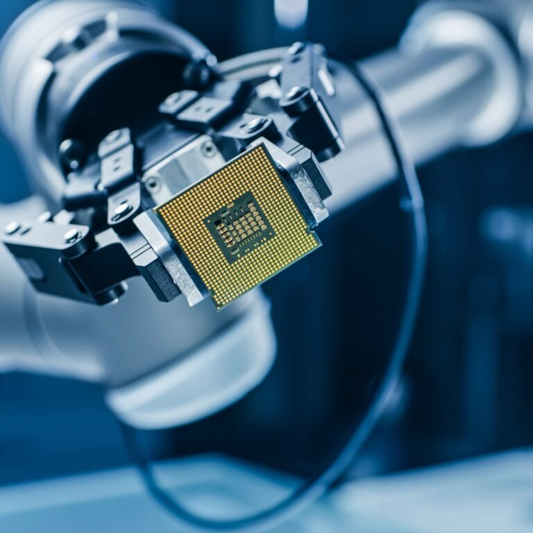 Robotic arm holding a microchip in a high-tech electronics lab.
